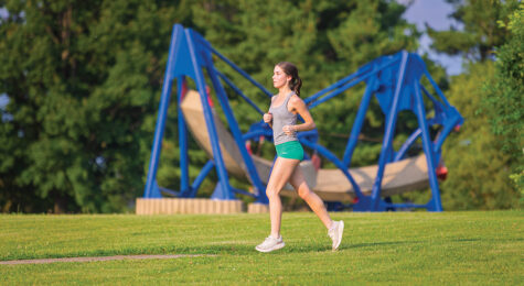 Runners run past sculptures that are part of the Donovan Sculpture Garden in Donovan Park in Peoria, Illinois.