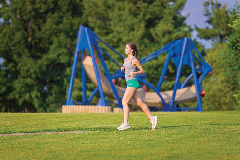 Runners run past sculptures that are part of the Donovan Sculpture Garden in Donovan Park in Peoria, Illinois.