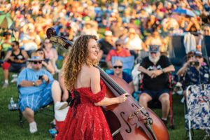 A woman in a red dress plays a stand-up bass at the Sunset Concert Series in Apple Valley, CA. Apple Valley is one of the small towns that make up the Victor Valley community.