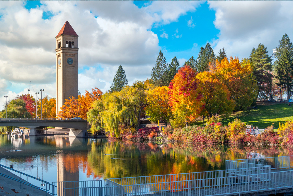 Vivid fall colors stick out at the Spokane, Washington Riverfront Park along the Spokane River with the Great Northern Clock Tower in view.