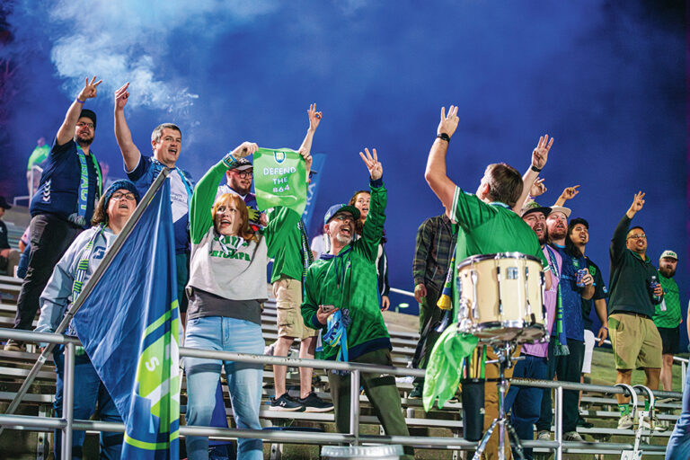 Greenville Triumph soccer fans chant and wave flags.