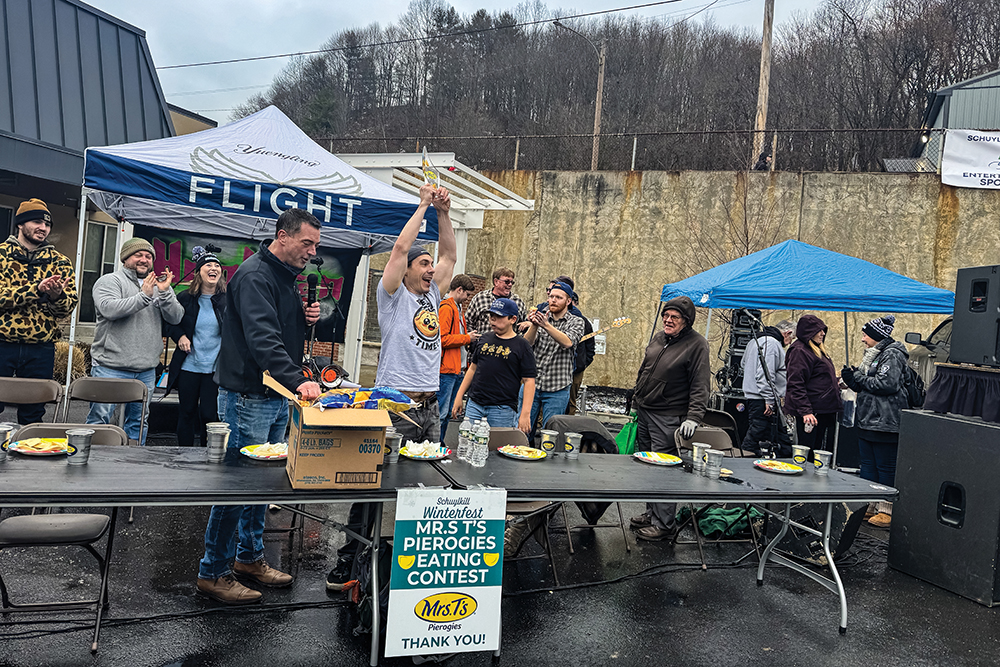 The winner of the Mrs. T’s Pierogy Eating Contest in Shenandoah, PA, hoists his trophy. Shenandoah is one of the regions of Schuylkill County, PA.