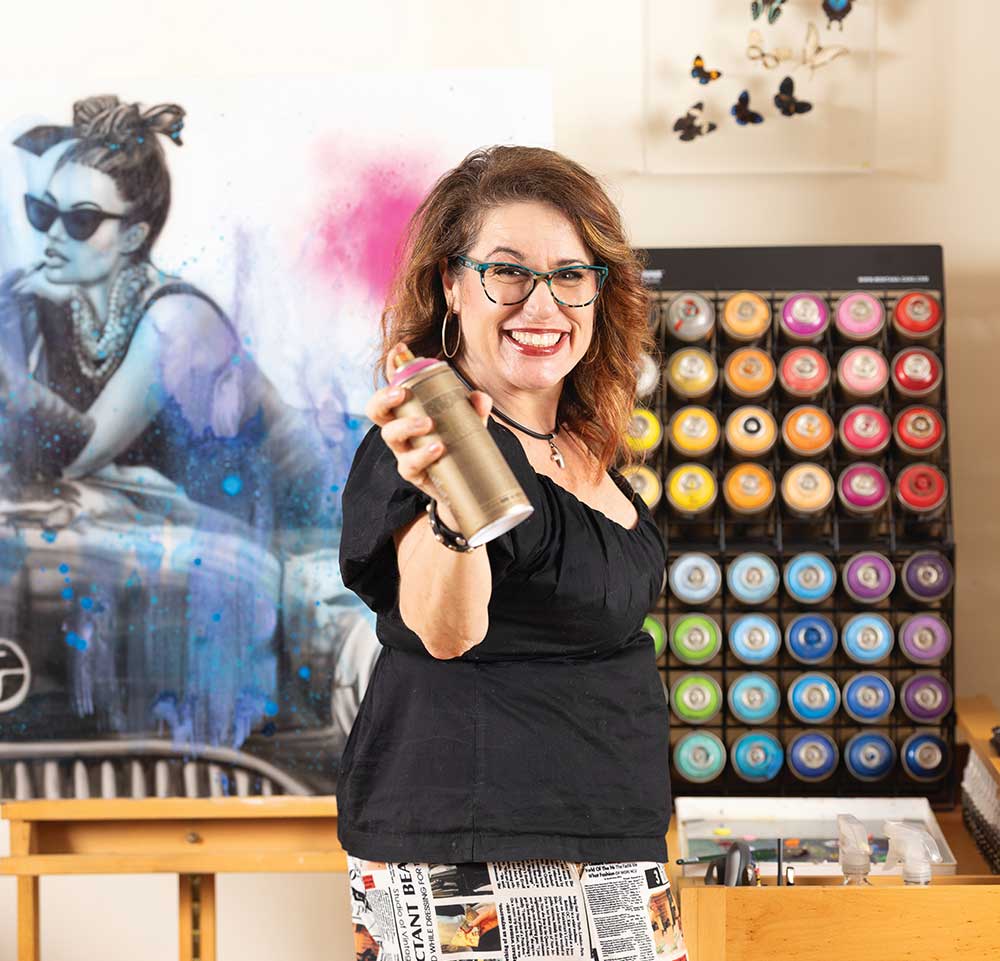 Graffiti artist Shen holds a can of spray paint with some of her paintings in her home studio in Madison, Tennesse. Her official aritst name is ShenShen210.