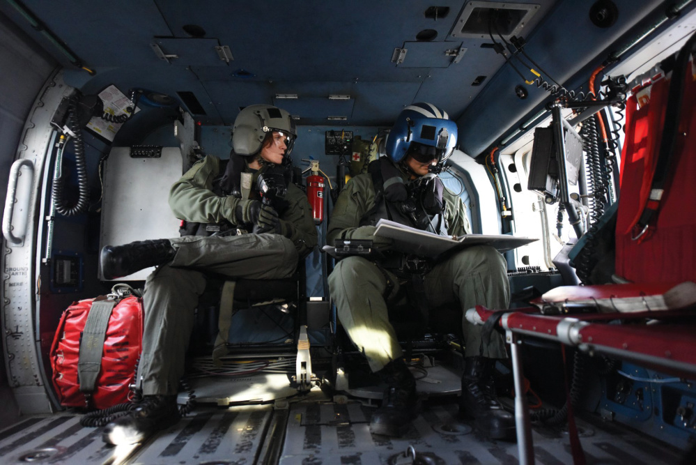 Coast Guard Petty Officers 2nd Class April Cook and Lawrence Mouton, aircrew members at Air Station Elizabeth City, North Carolina, practice using the electronic sensor on board an MH-60 Jayhawk helicopter during a training flight along North Carolina coast