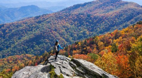 Woman on top of the mountain enjoying beautiful fall scenery. Girl hiking in the autumn mountains. Blue Ridge Mountains, near Asheville, North Carolina, USA