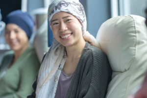 Three women sitting in chairs in a hospital as they undergo Chemotherapy treatment.