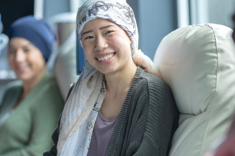 Three women sitting in chairs in a hospital as they undergo Chemotherapy treatment.