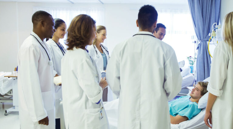 Doctor and residents examining patient in hospital room