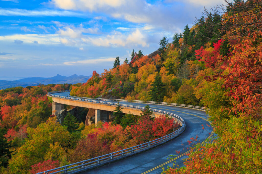Linn Cove Viaduct on the Blue Ridge parkway in the fall season. Road winding through the mountains with autumn colors and blue vibrant morning skies.