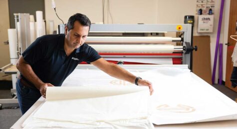 Ahsan Irshad co-owner of AlphaGraphics in Brentwood, Tennessee, laminates a printed sign at his shop.
