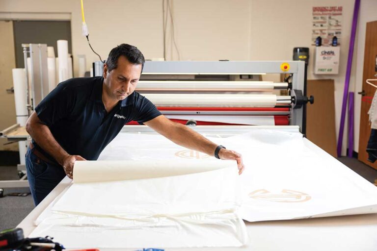 Ahsan Irshad co-owner of AlphaGraphics in Brentwood, Tennessee, laminates a printed sign at his shop.