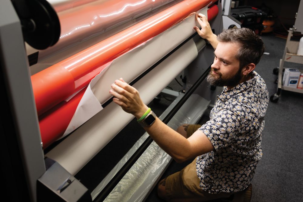 An employee works on printing a sign at AlphaGraphics in Brentwood, Tennessee.