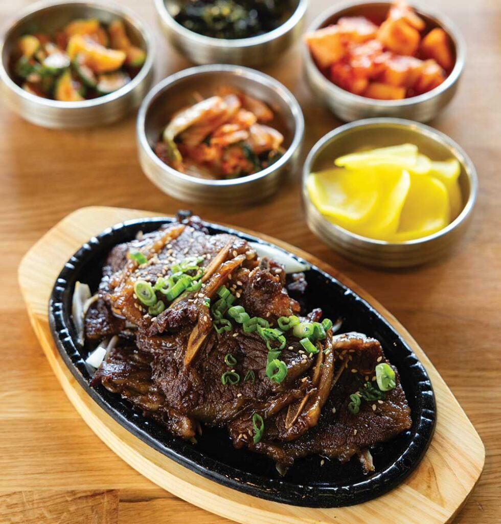 Galbi (beef short rib) surrounded by Banchan (side dishes) and steamed rice at Mad for Galbi restaurant in Nolensville, Tennessee.