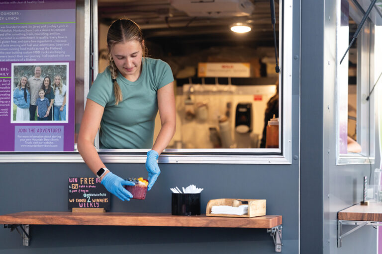 A young woman serves acai smoothie bowls from the Mountain Berry Bowls food truck at Downtown Commons in Twin Falls, Idaho.