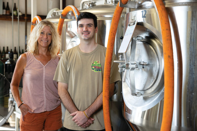 Intern Harrison Plumlee and Arconic internship program director Jackie Taylor stand next to a brewing tank containing seltzer that Harrison helped brew at Peaceful Side Brewing in Maryville.