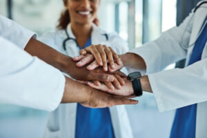 Closeup shot of a group of medical practitioners joining their hands together in a huddle