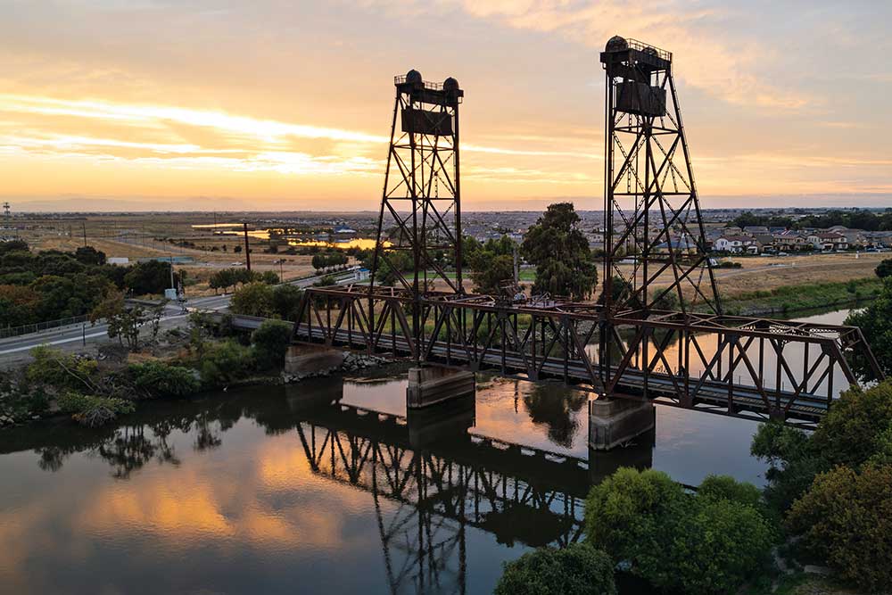 The Mossdale railroad bridge spans the San Joaquin River in front of the River Islands master planned residential community in Lathrop, CA. San Joaquin Co.