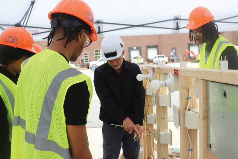 Winston-Salem/Forsyth County Schools students watch an electrician demonstrate proper wiring of a light fixture.