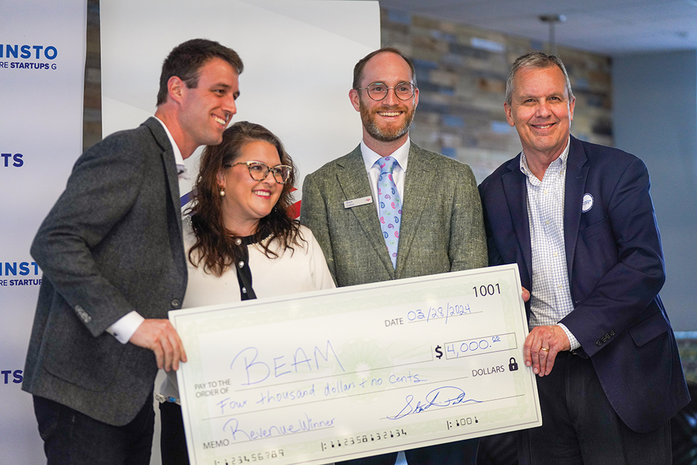 Four business people pose with a check at Winston Starts in Winston-Salem, NC. Spark provides entrepreneurial resources to new businesses in the region.