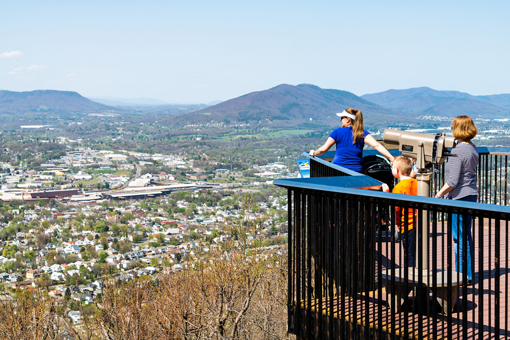 Roanoke, USA - April 18, 2018: City in Virginia during spring with people family during sunny day looking at view from Mill Mountain Park