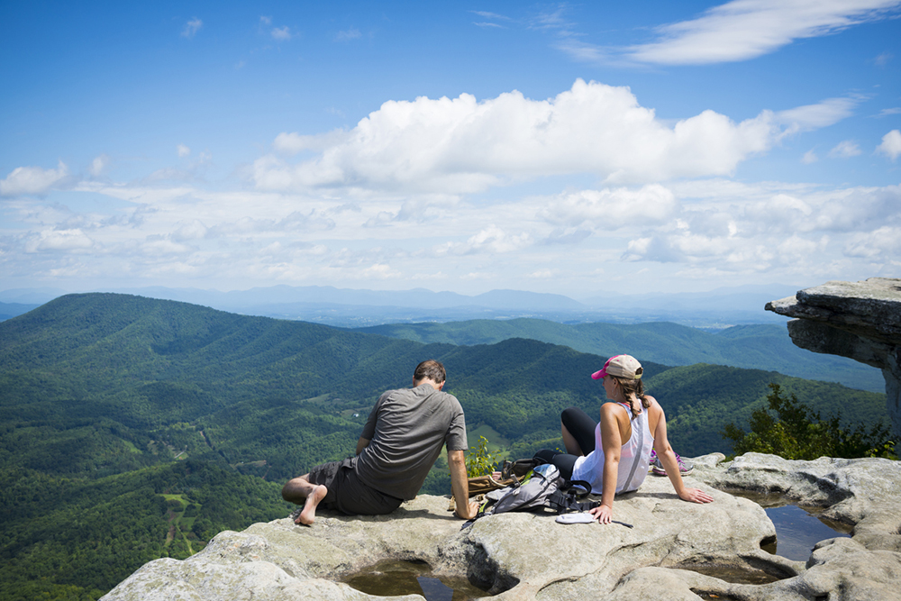 Two hikers enjoy the view of the Appalachian Mountains from McAfee Knob on Catawba Mountain, near Roanoke, Virginia.