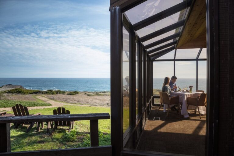 Couple dining by ocean with meadow in foreground in northern California.