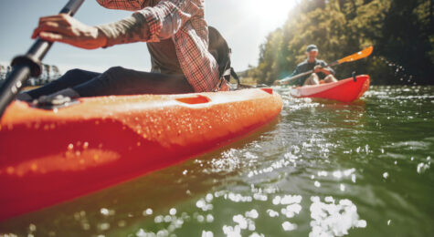 Cropped image of woman kayaking with a man in background. Couple canoeing in a lake on a summer day.