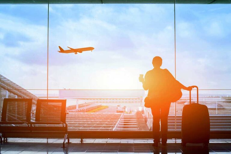 Person watches an airplane take off into the sunset.