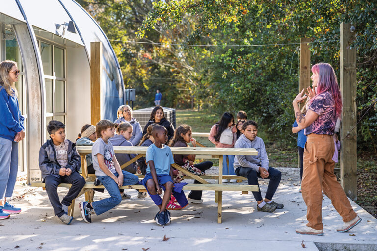Maddy VanMiddlesworth speaks to a group of Rock Ridge Elementary students about soil in the outdoor classroom at the North Carolina Museum of Natural Sciences at Contentnea Creek.