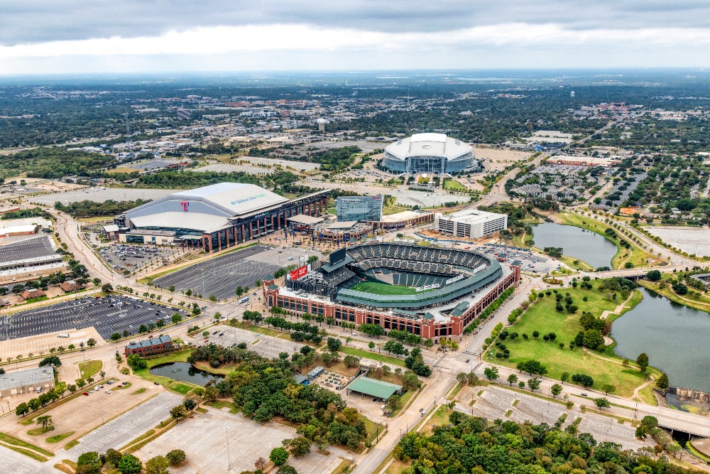 An aerial view of the three professional sports venues on adjacent properties just east of Dallas, Texas, including Globe Life Field, the former home of baseball's Texas Rangers, Globe Life Park, the new home of the Texas Rangers, and AT&T Stadium, the home of the NFL Dallas Cowboys.
