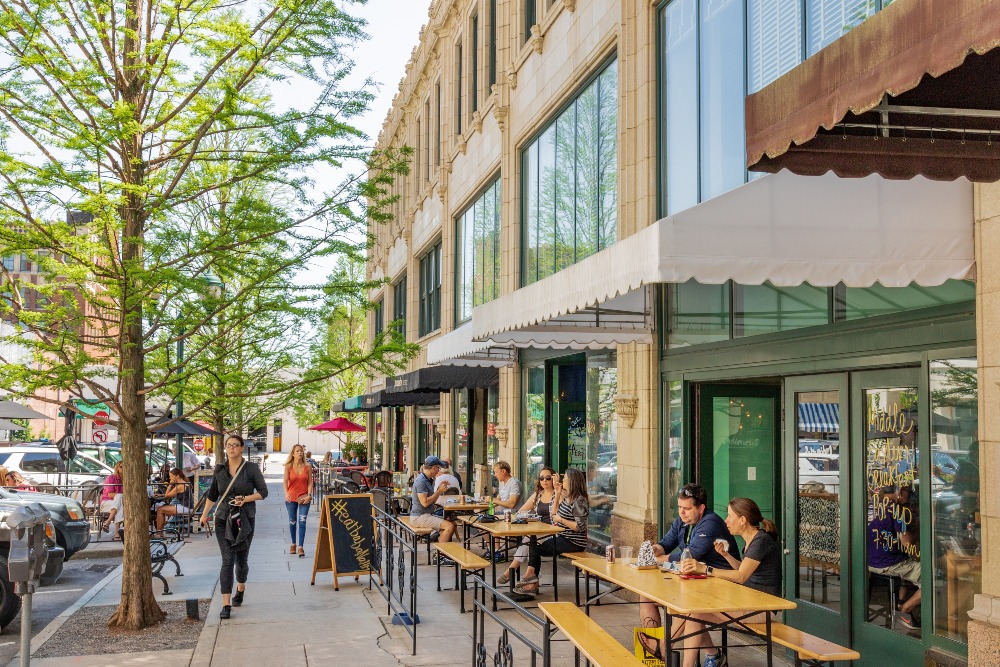 Diners relax at outdoor tables along Page Avenue in downtown Asheville, NC, on a warm, sunny spring day.