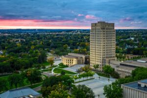 The State Capitol building rises against a dramatic red and blue sunset in Bismarck, North Dakota.