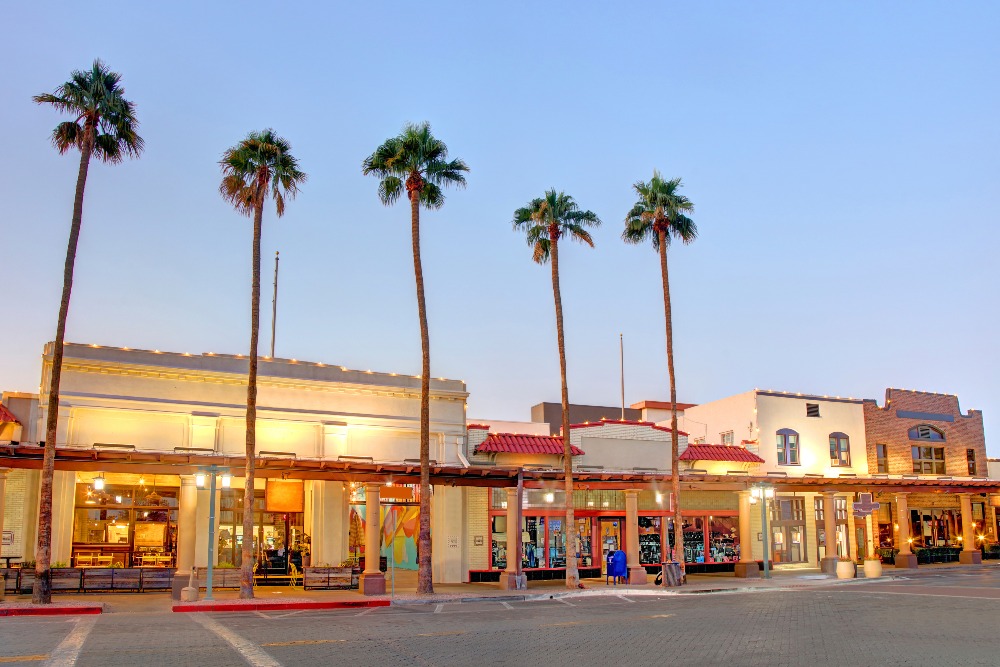 Palm trees rise above a low-profile retail area lit up a dusk in Chandler, AZ.