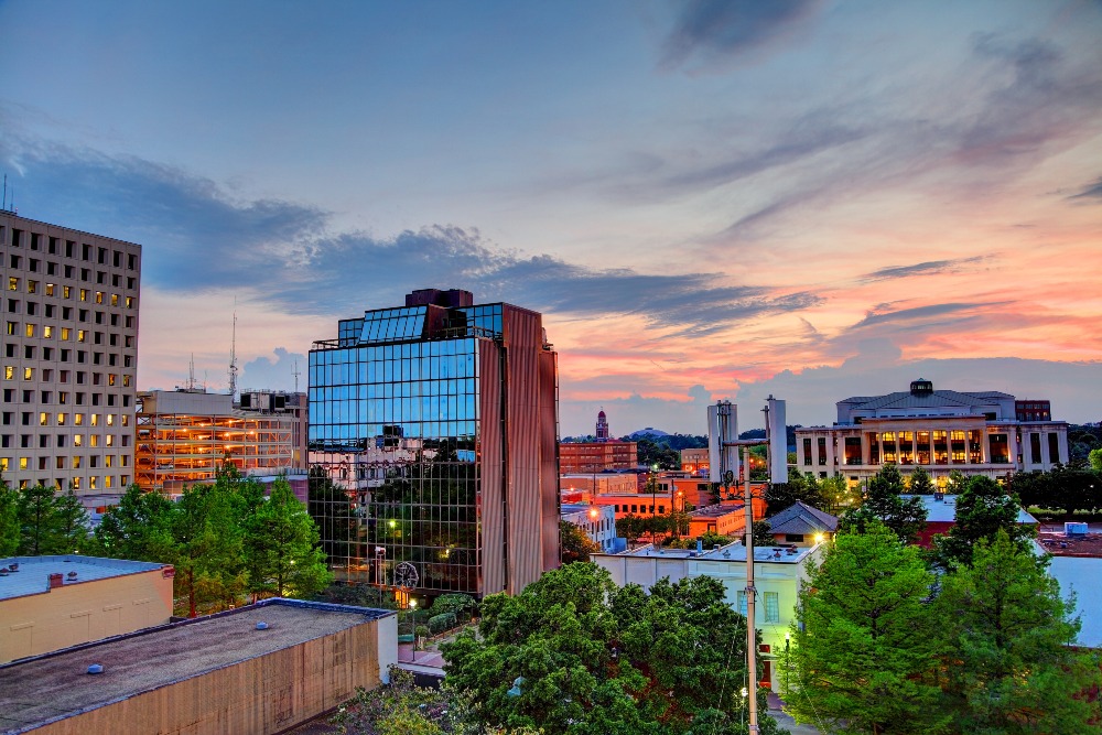 A mix of modern high rises and older buildings in downtown Lafayette, LA, at sunset.