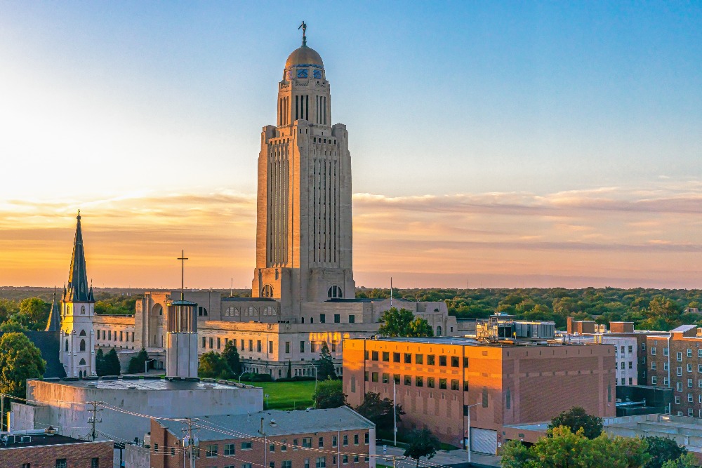 The Nebraska State Capitol towers over downtown Lincoln, NE, at sunrise.