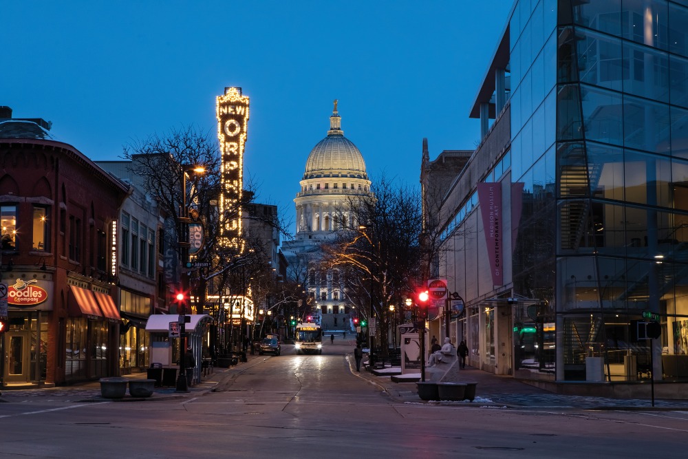 A view of State Street in downtown in Madison, WI, at dusk, with the Orpheum Theater and the Wisconsin State Capitol.