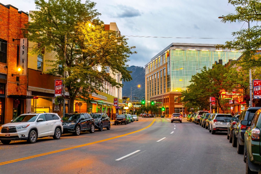 The streets of downtown Missoula, MT, are lit by a warm glow from streetlights and businesses as the day turns to dusk.