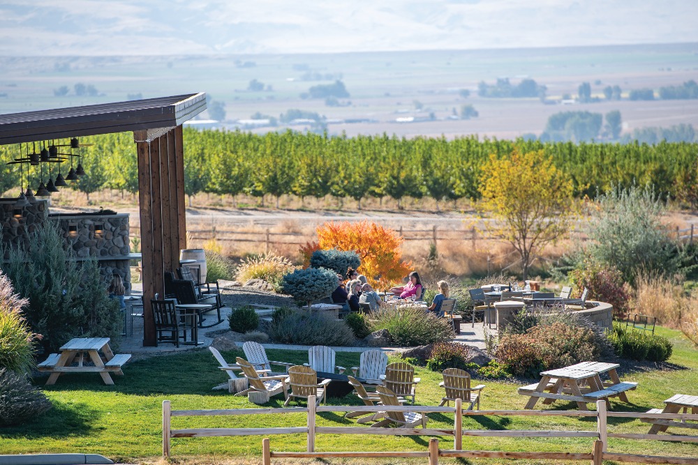 Visitors to Sawtooth Winery in Caldwell, Idaho, relax outdoors with views of the tasting room and vineyards.