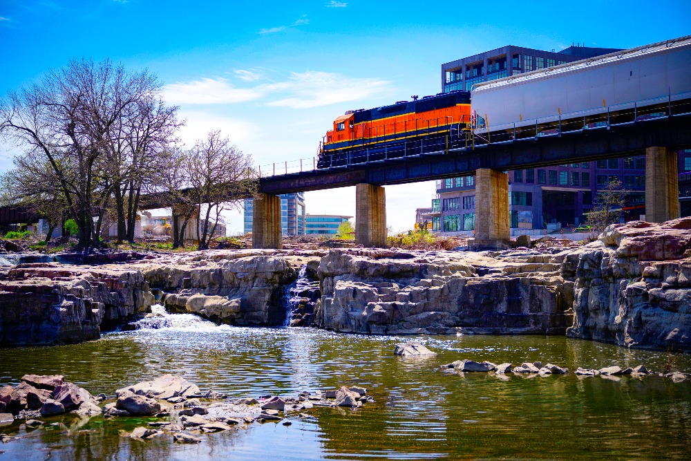 A train crosses over Falls Park on the Big Sioux River in Sioux Falls, South Dakota. The falls are one of the highlights of living in Sioux Falls.