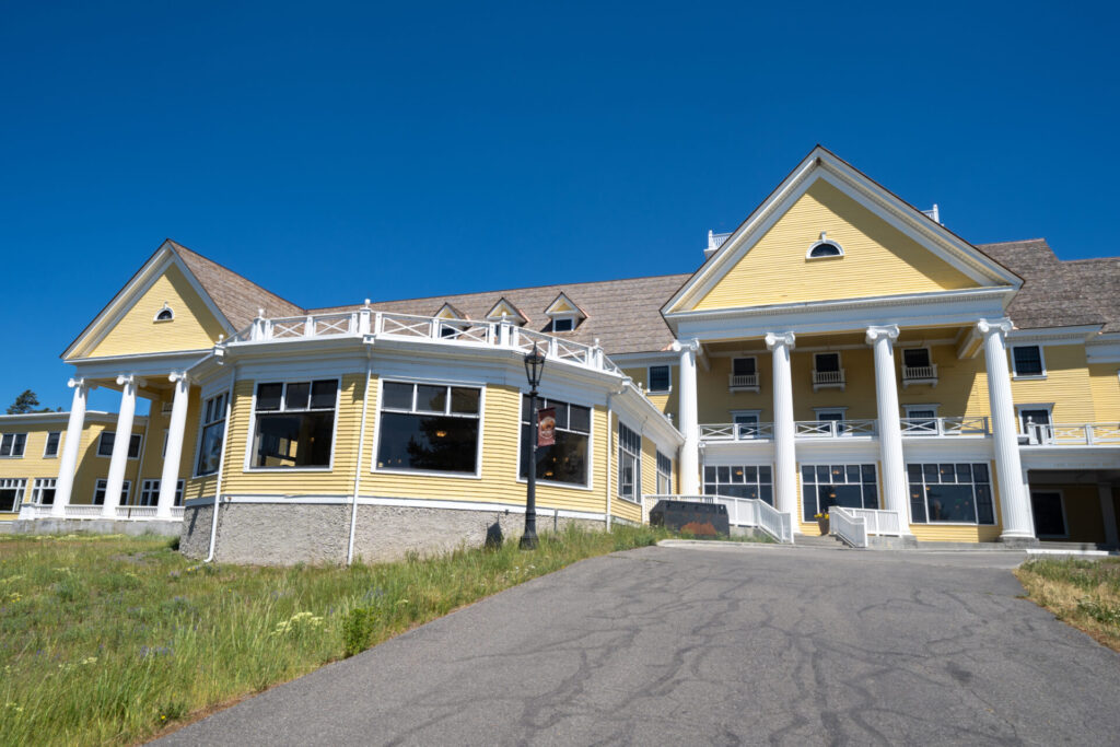 Exterior of the yellow Lake Yellowstone Hotel with white columns in Yellowstone National Park.