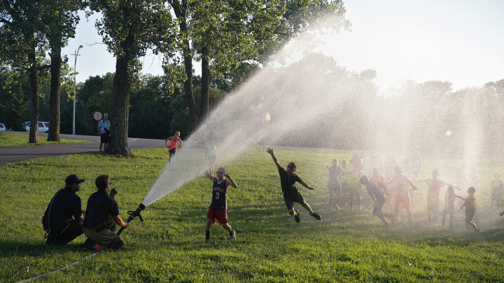 A scenic shot of a water spray in the park and kids playing under it in Lenexa, Kansas.