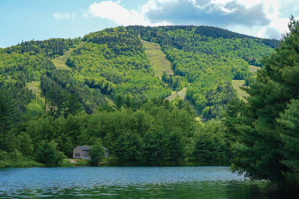 Water and green mountains during the warm months at Attitash Mountain Resort.