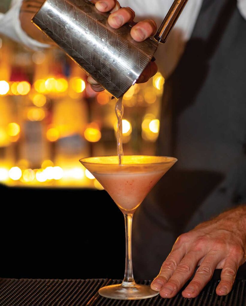 Close-up of a bartender pouring a cocktail behind the bar at the Library Restaurant in downtown Portsmouth.