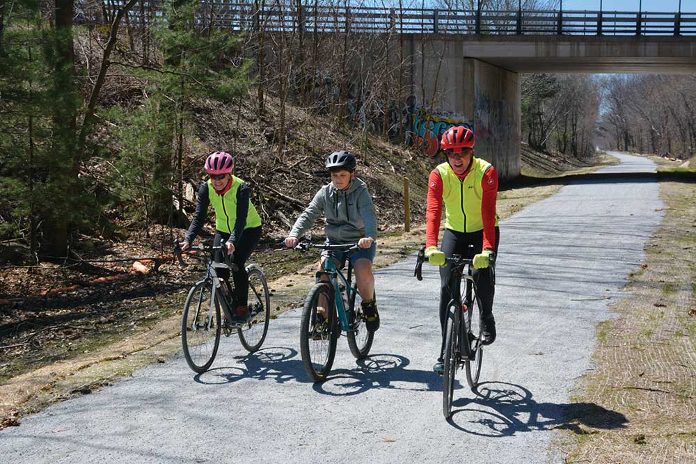 People pedal along a paved greenway / path.