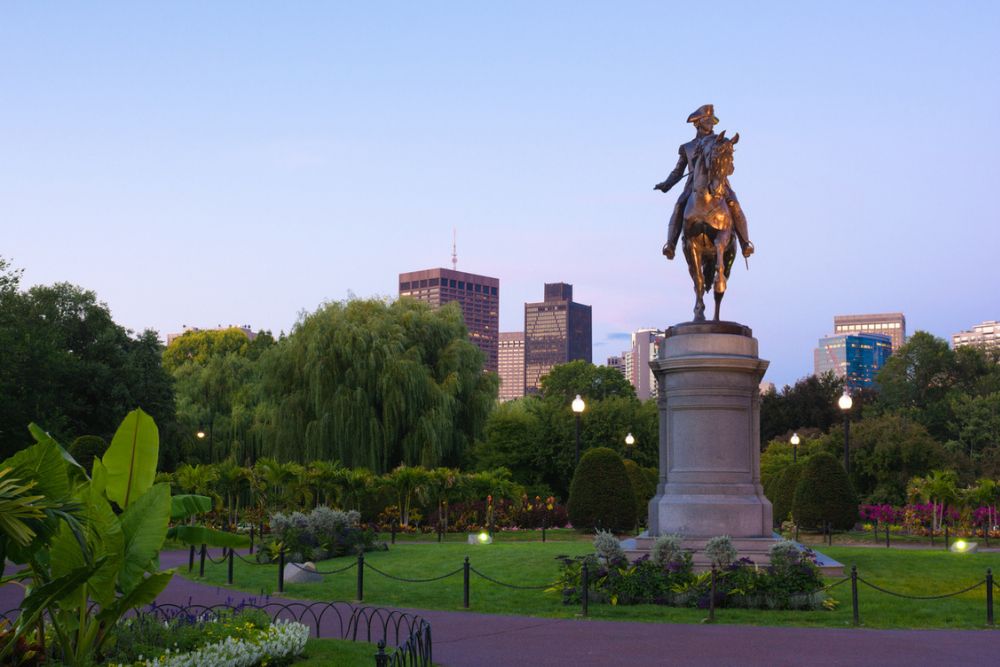 Equestrian bronze statue of General George Washington in the Boston Public Garden surrounded by green trees.