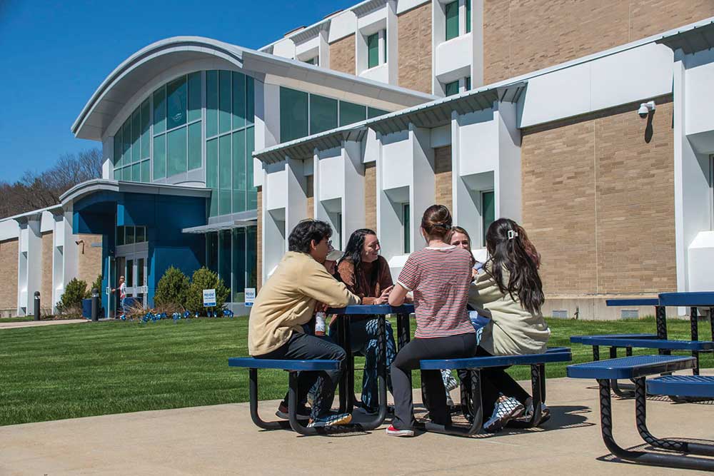 Students sit together outside on a sunny day.