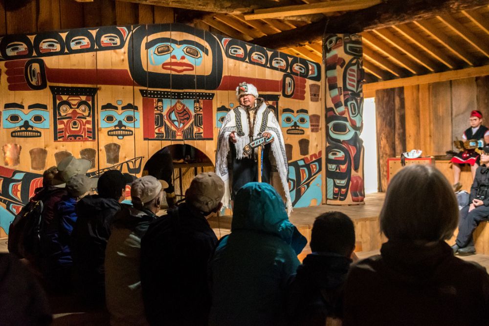 An indigenous guide discussing native Tlingit heritage inside the Jilkaat Kwaan Heritage Center in Alaska.