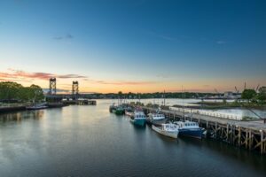 A view of boats on the water with the large metal structure of the Memorial Bridge in Portsmouth NH.