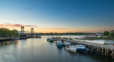 A view of boats on the water with the large metal structure of the Memorial Bridge in Portsmouth NH.