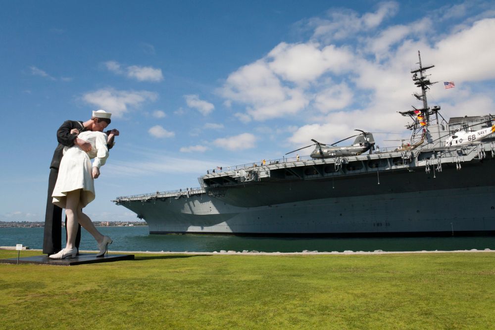 The massive USS Midway Museum aircraft carrier docked in the San Diego harbor under a clear sky.